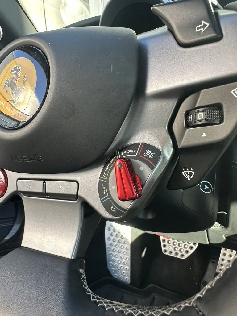 Vue rapprochée du volant de la Ferrari GTC4 Lusso gris foncé, mettant en valeur la molette de modes de conduite rouge.