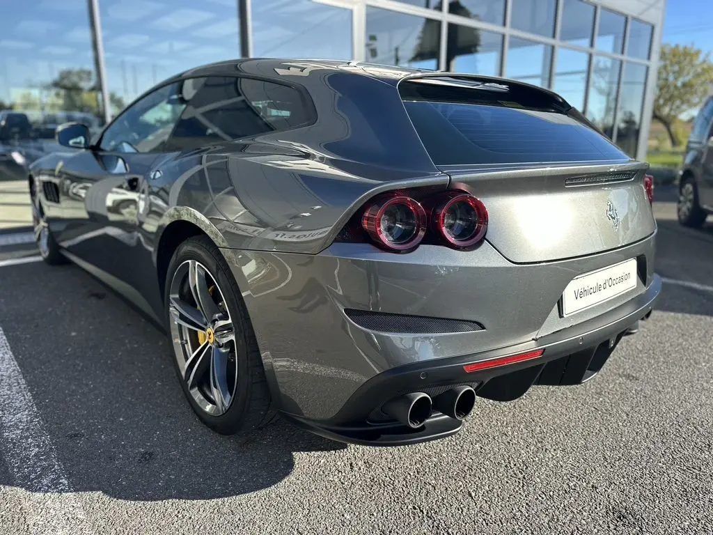 Ferrari GTC4 Lusso gris foncé vue 3/4 arrière droit, avec feux ronds et double sortie d'échappement.