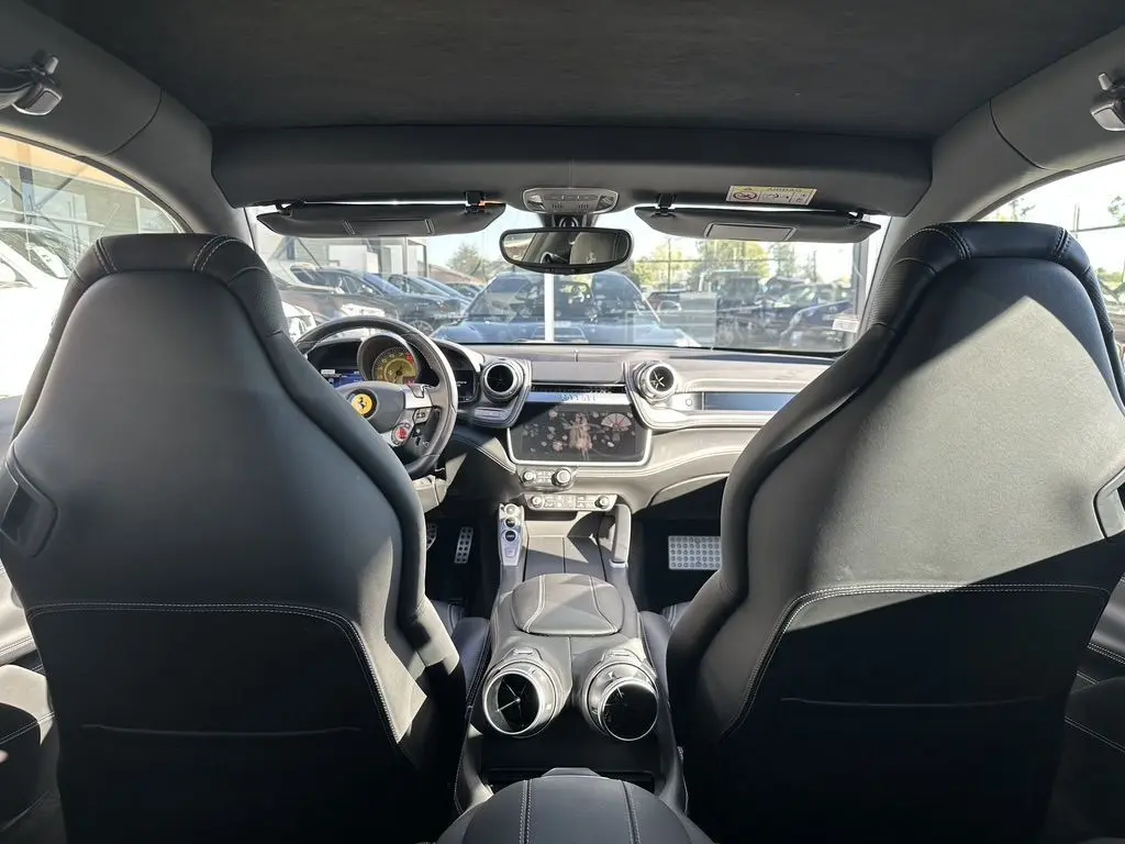 Vue intérieure avant de la Ferrari GTC4 Lusso gris foncé, avec sièges sport en cuir et tableau de bord moderne.