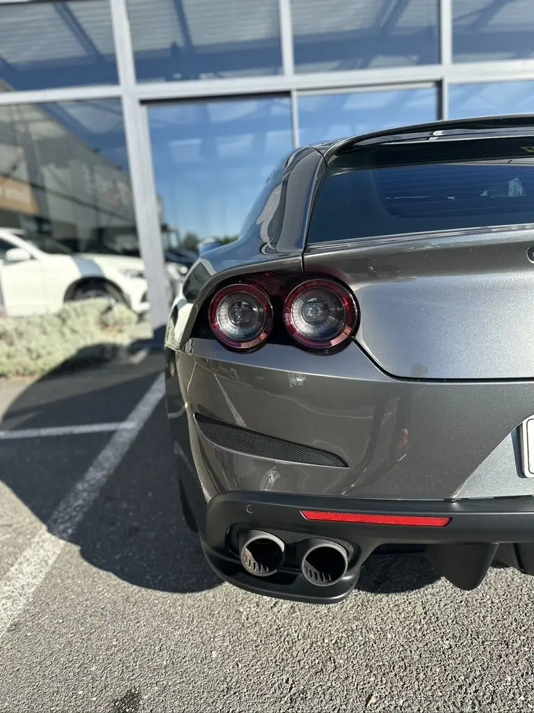 Vue arrière droite d'une Ferrari GTC4 Lusso gris foncé avec feux ronds et double sortie d'échappement visible.