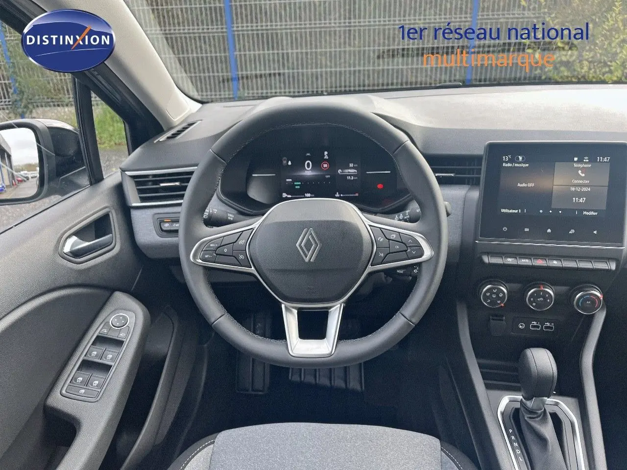 Vue intérieure centrée sur le volant et tableau de bord de la Renault Clio 2024, avec écran tactile et commandes modernes.