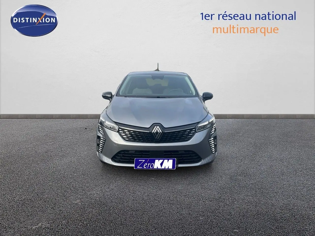 Vue frontale d'une Renault Clio TCE 90CH X-TRONIC TECHNO gris schiste métal avec feux LED allumés sur fond neutre.