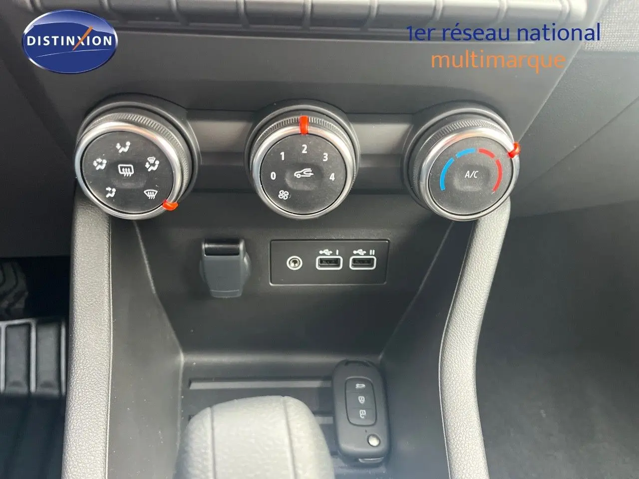 Gros plan sur la console centrale de la Renault Clio 2024 montrant les commandes de climatisation et ports USB.
