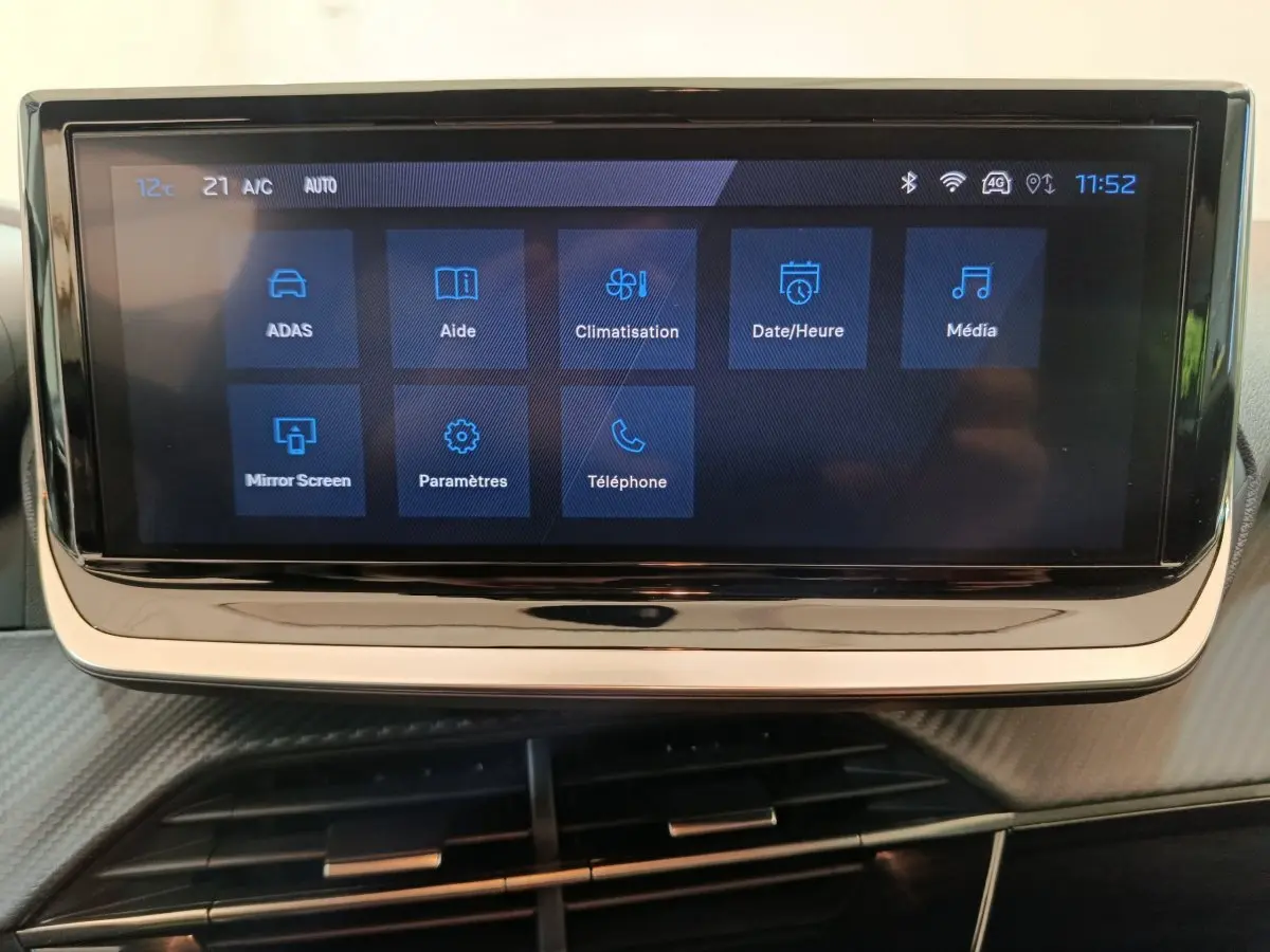 Écran tactile central affichant les options du menu dans l'habitacle d'une Peugeot 208 gris clair.