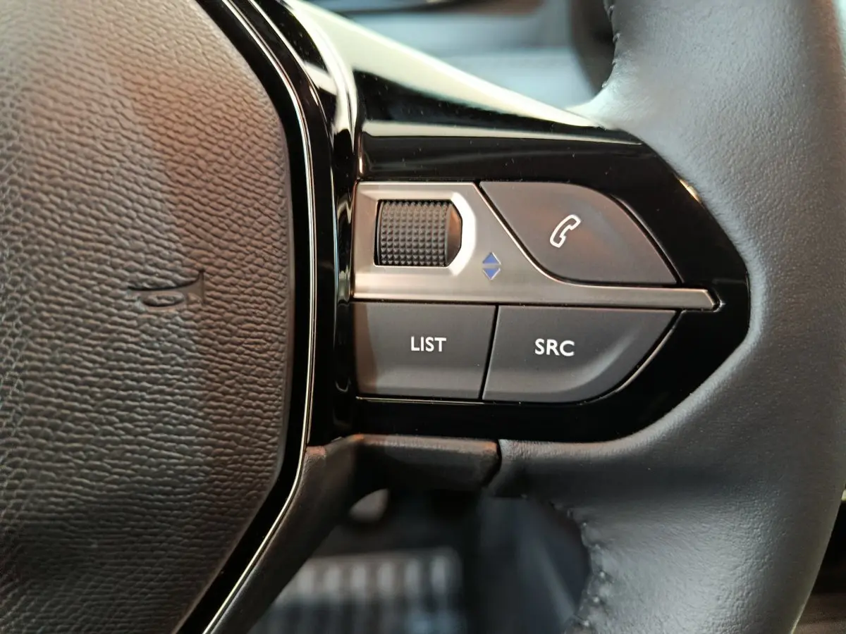 Gros plan sur les commandes du volant cuir noir de la Peugeot 208 PureTech 100 S&S Allure 2025.