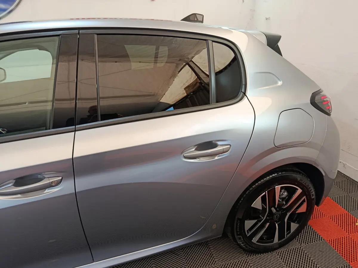 Vue latérale droite sur l'arrière d'une Peugeot 208 gris clair avec jante alliage et feux arrière LED.