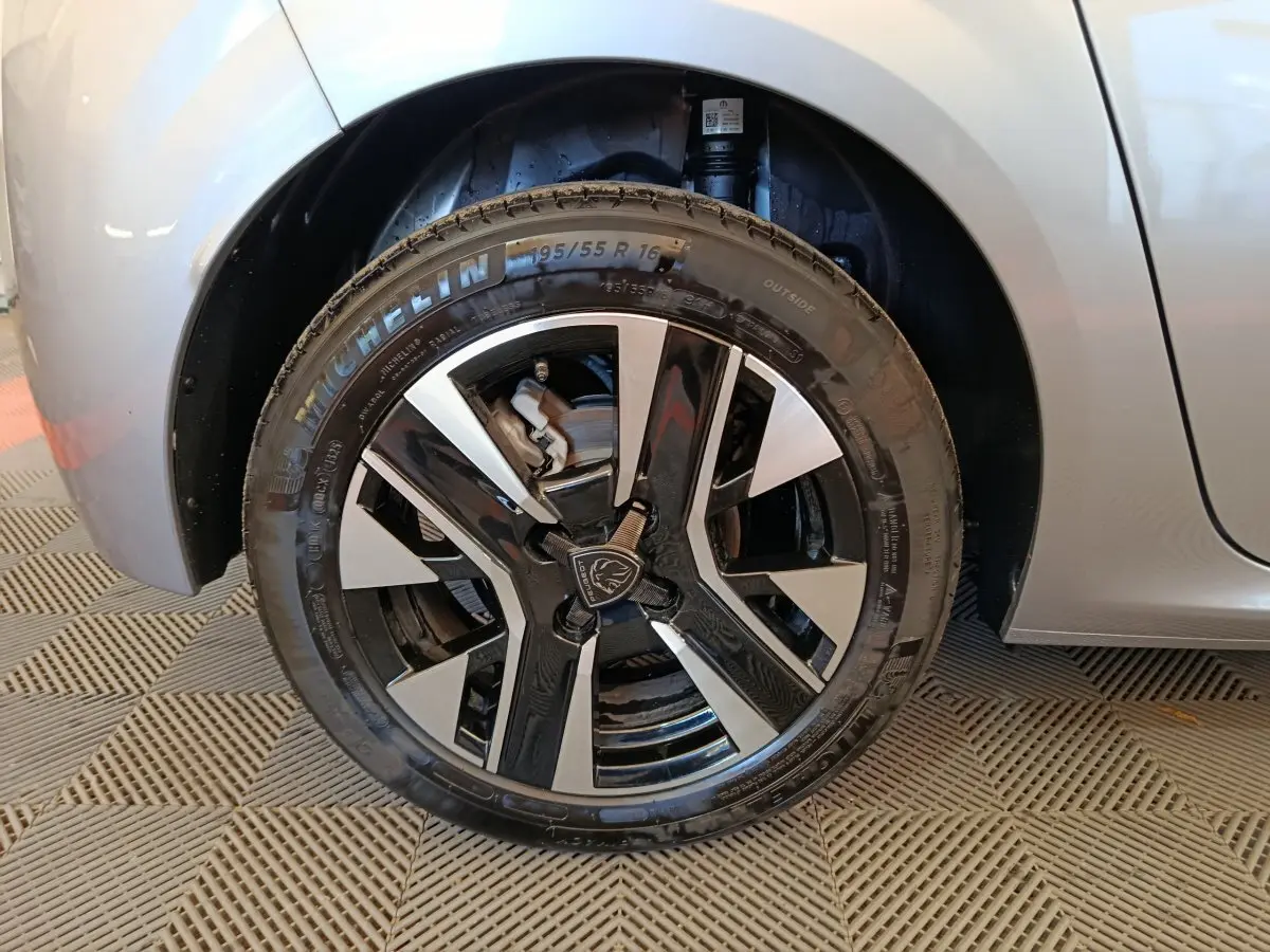 Gros plan sur la roue avant gauche gris clair de la Peugeot 208 2025 avec jante alliage noire et argentée.