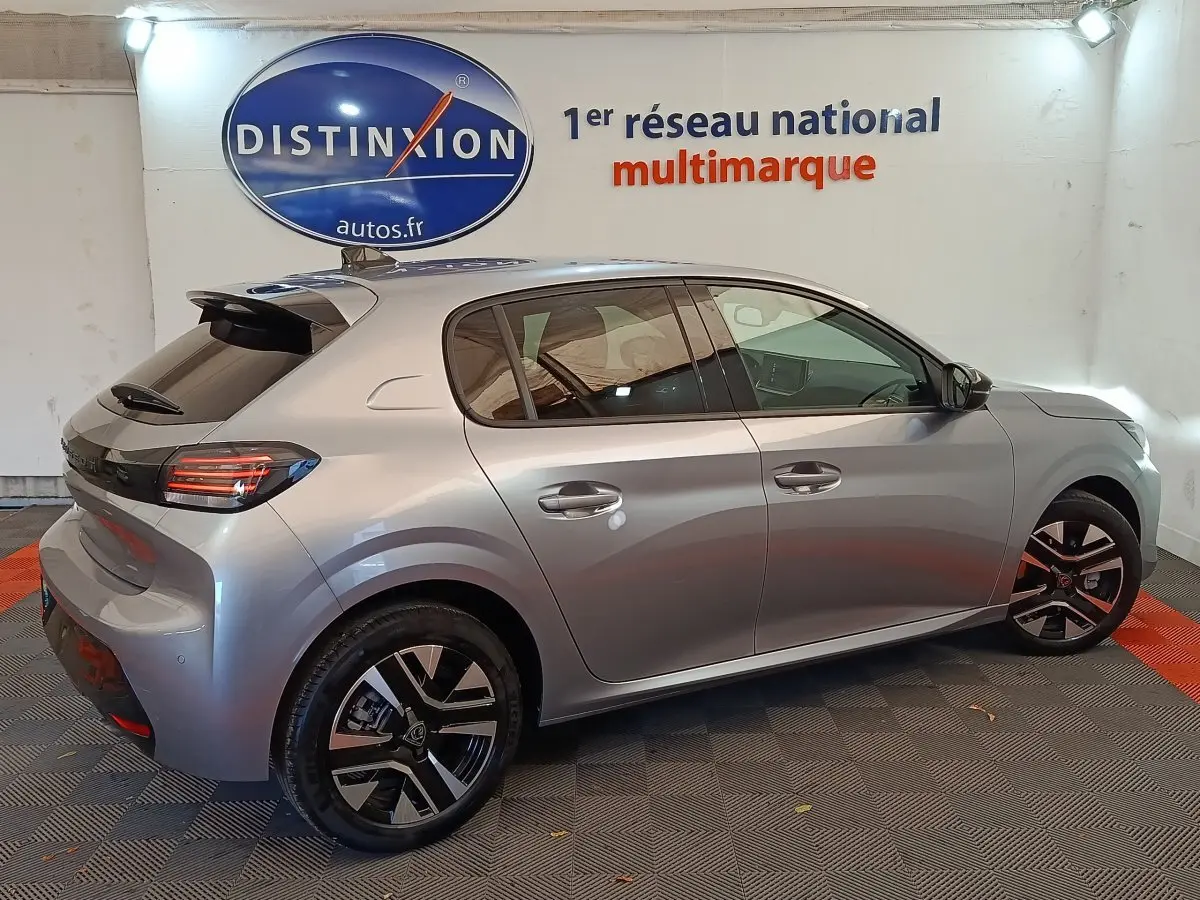 Vue latérale droite d'une Peugeot 208 PureTech 100 S&S Allure gris clair avec jantes noires et détails rouges.