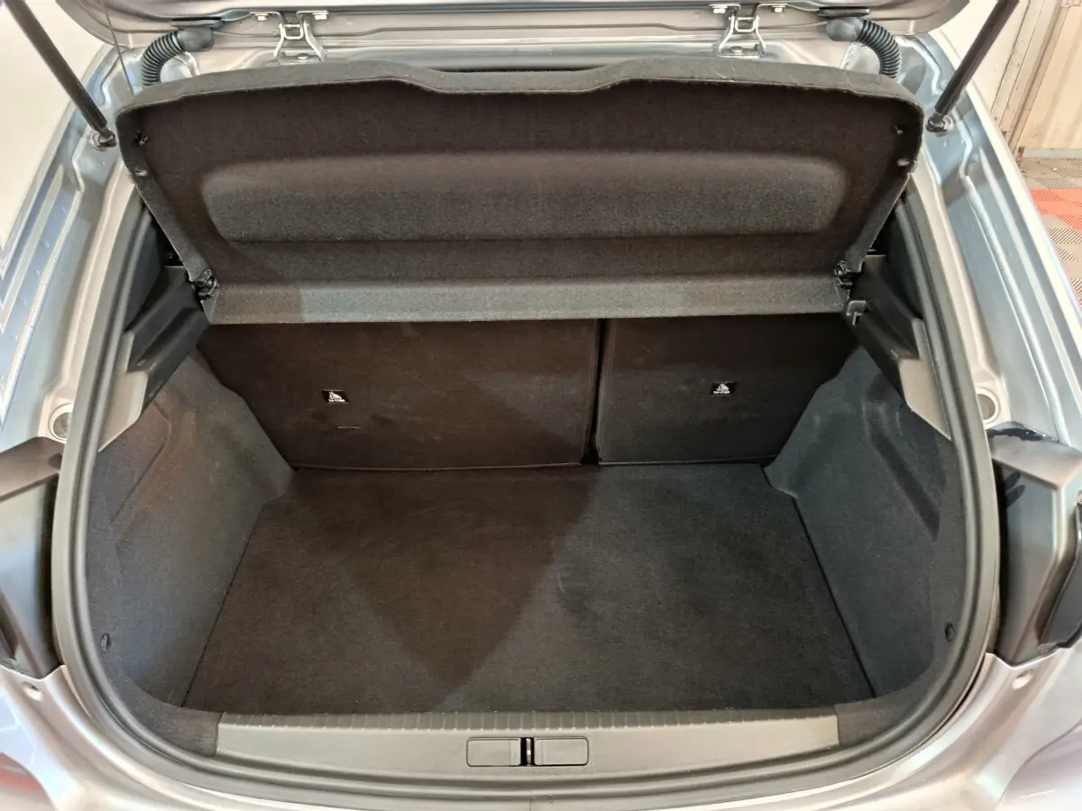 Coffre ouvert vu de dessus d'une Peugeot 208 gris clair, montrant un espace de chargement propre et spacieux.