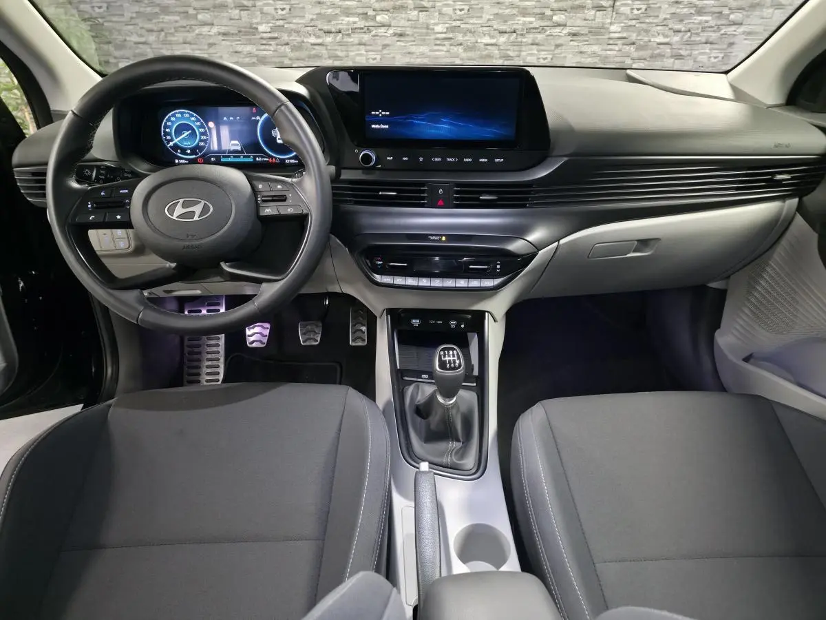 Vue intérieure avant du Hyundai Bayon 2025 essence noir, volant cuir, écran tactile et levier de vitesse manuel.