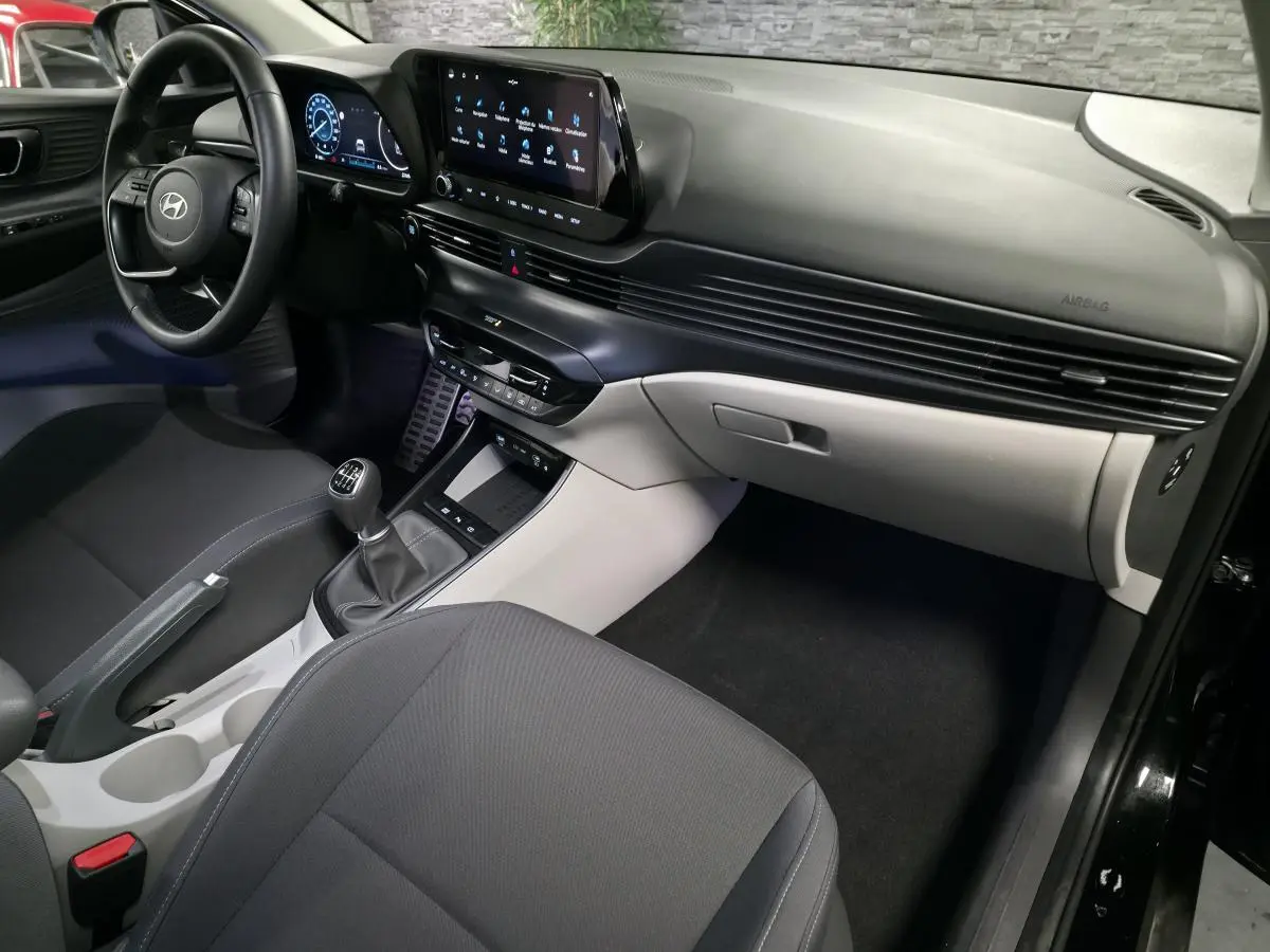 Vue intérieure côté passager de la Hyundai Bayon 2025 noire, avec tableau de bord bi-ton noir et gris clair et écran tactile.