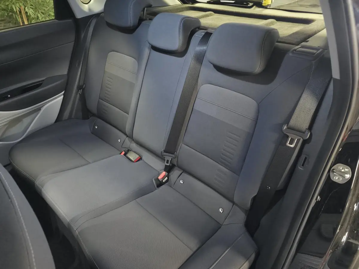 Vue intérieure des sièges arrière gris foncé du Hyundai Bayon 2025, avec ceinture de sécurité et porte ouverte côté droit.