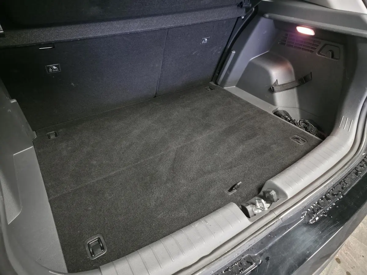 Coffre ouvert vu de l’arrière d’une Hyundai Bayon noire 2025, tapis noir et éclairage intérieur visible.