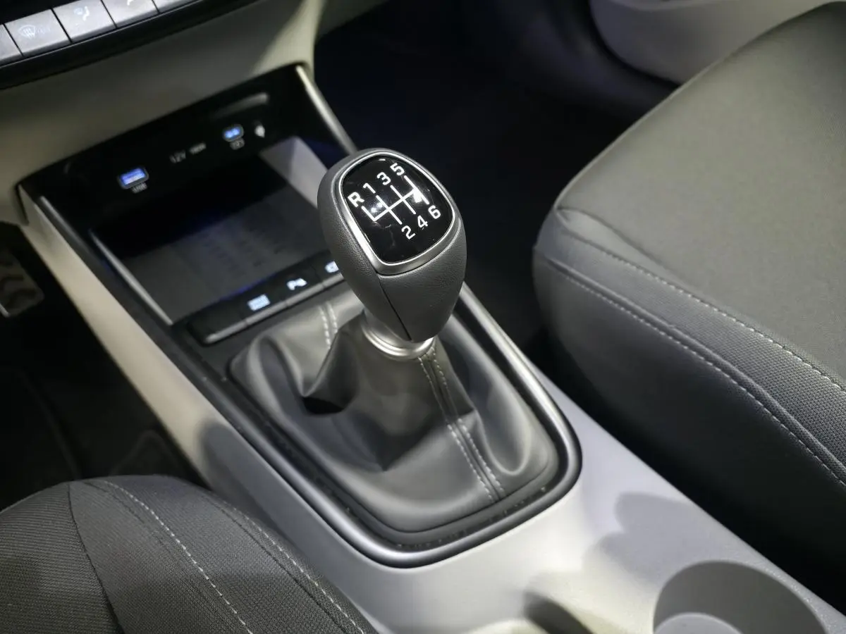 Gros plan sur le levier de vitesses manuel noir du Hyundai Bayon 2025, entouré de sièges tissu gris foncé.