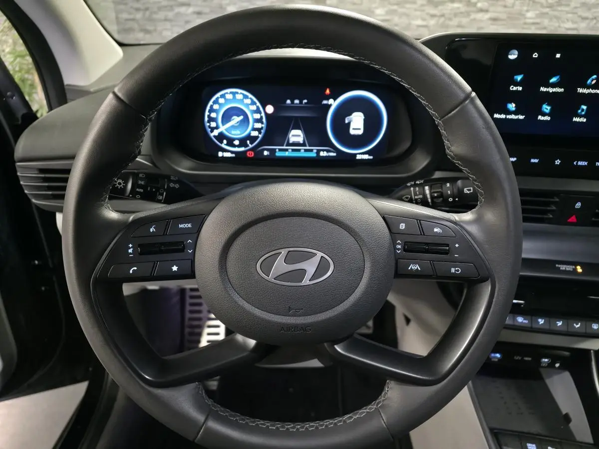 Vue intérieure centrée sur le volant cuir noir et le tableau de bord numérique du Hyundai Bayon 2025.