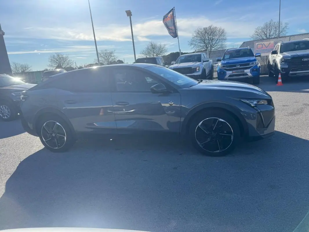 Peugeot 408 gris vue de profil côté droit, avec jantes alliage noires et vitres teintées, stationnée en extérieur.