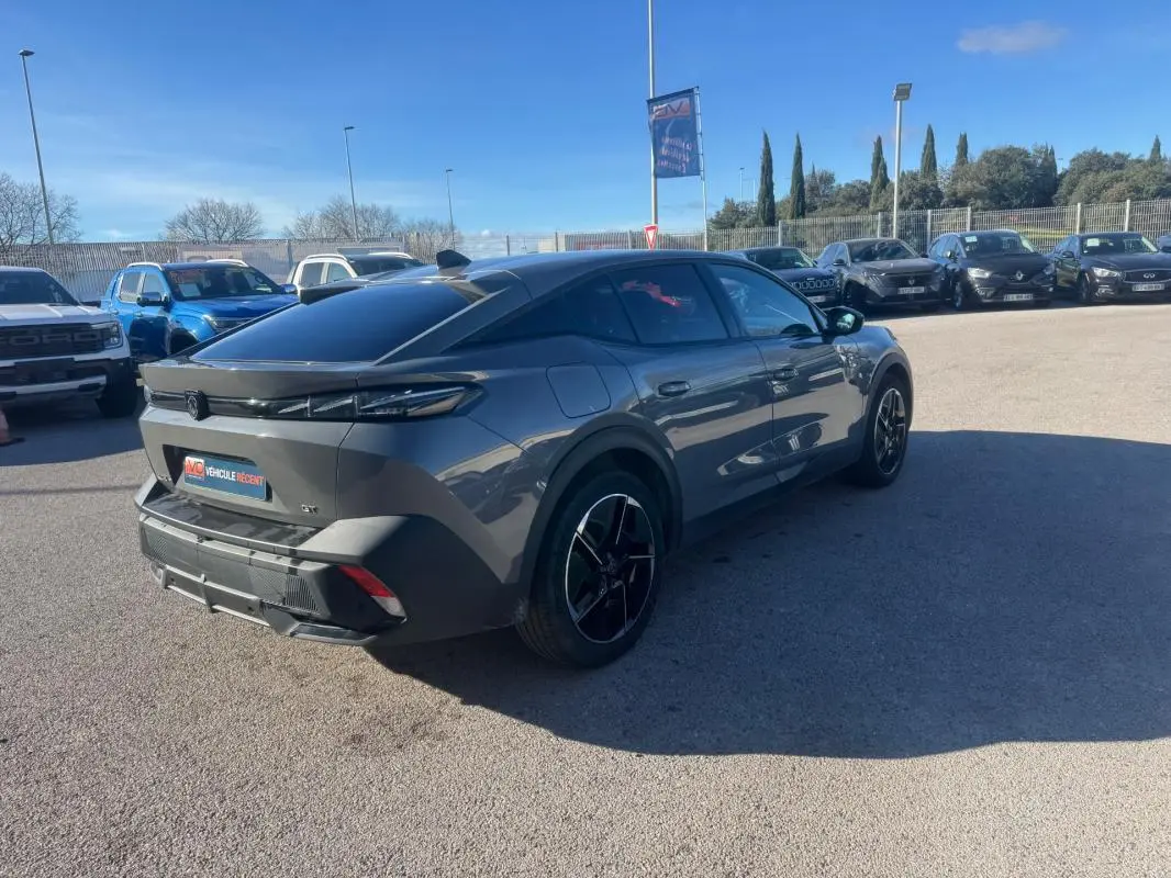 Peugeot 408 gris en 3/4 arrière droit, avec jantes alliage noires et vitres teintées, stationnée en extérieur.