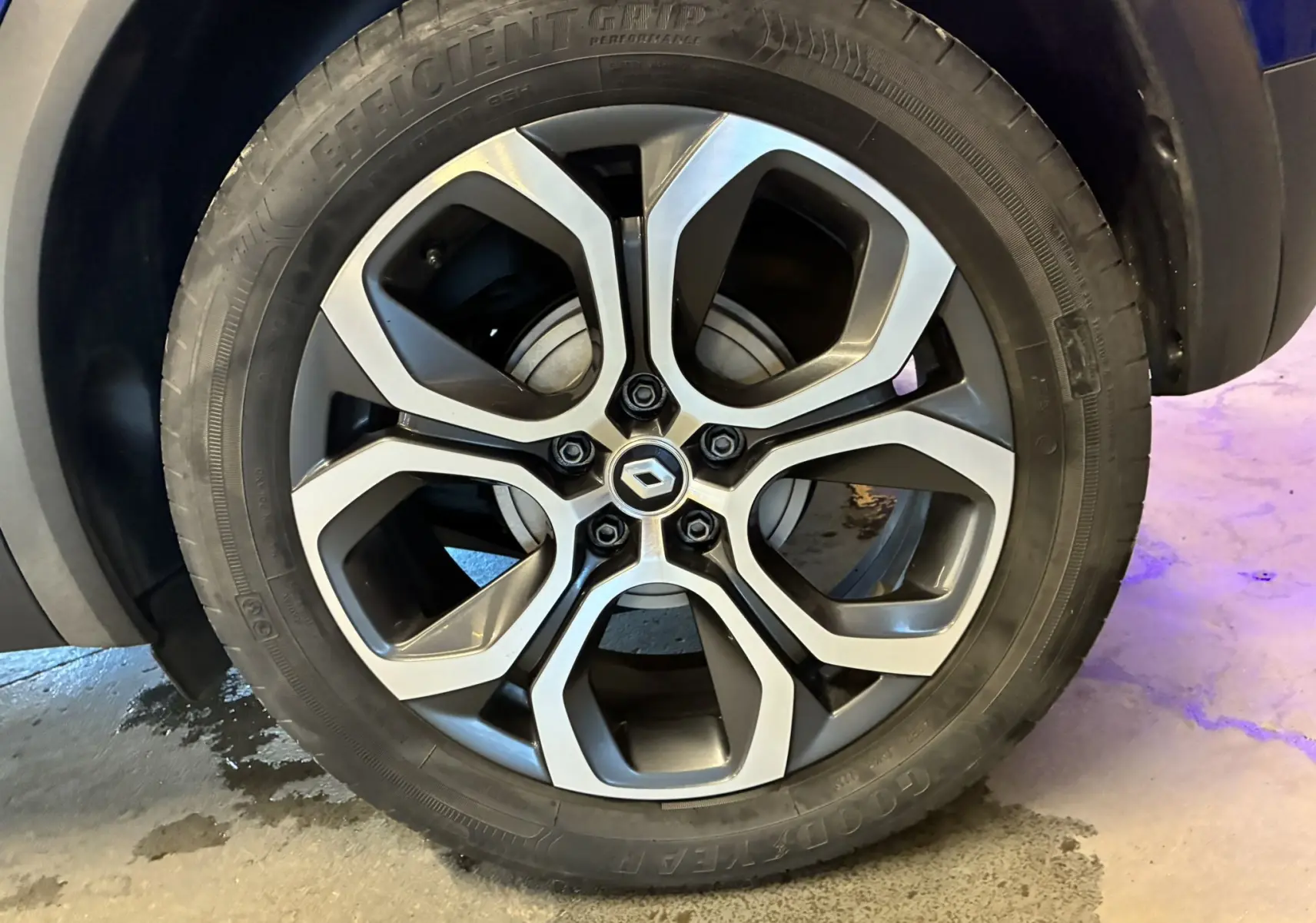 Gros plan sur la roue arrière droite d'un Renault Captur bleu 2021, avec passage de roue noir et sol béton.