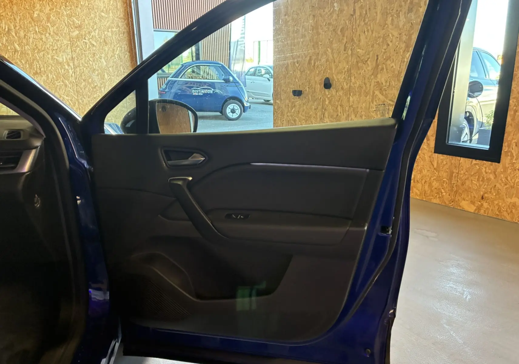 Vue intérieure de la porte avant gauche bleu du Renault Captur 1.3 TCE 140 Intens, avec poignée et commandes de vitre visibles.