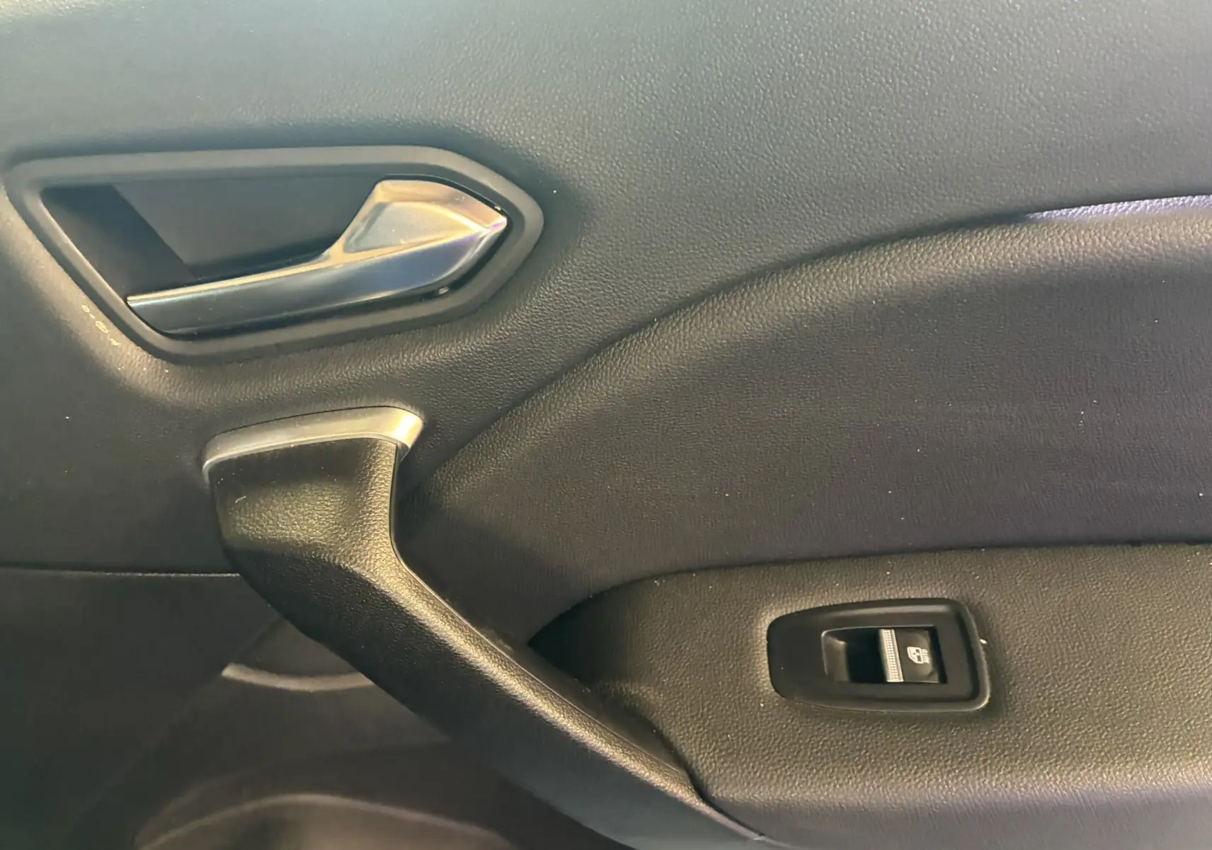 Détail de la poignée intérieure et commande de lève-vitre sur la porte côté droit du Renault Captur bleu 2021.