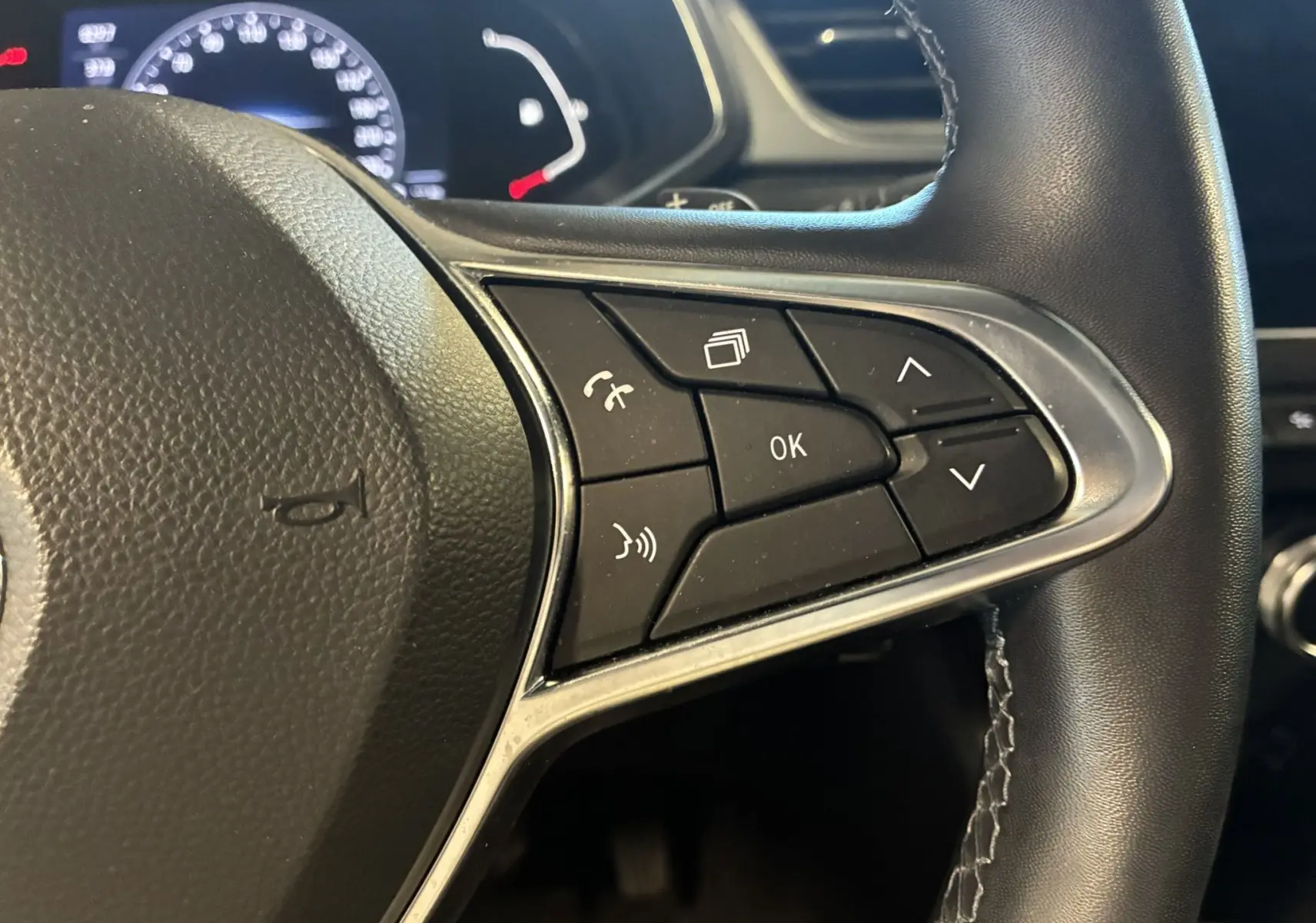 Gros plan sur les commandes multifonctions à droite du volant noir du Renault Captur 2021, avec boutons de navigation et téléphone.