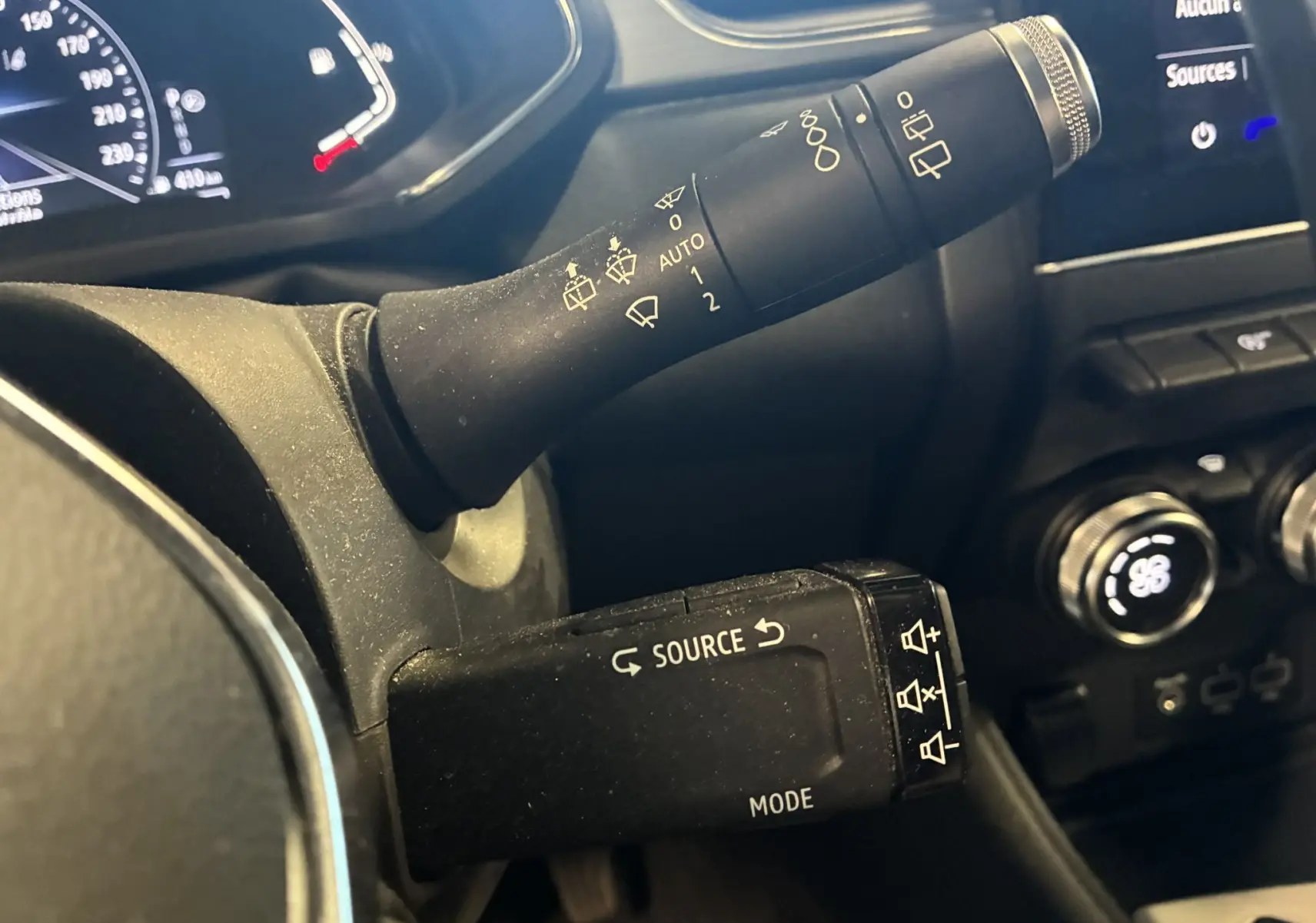 Gros plan sur les commandes au volant du Renault Captur bleu 2021, avec levier d’essuie-glace et commande multimédia.