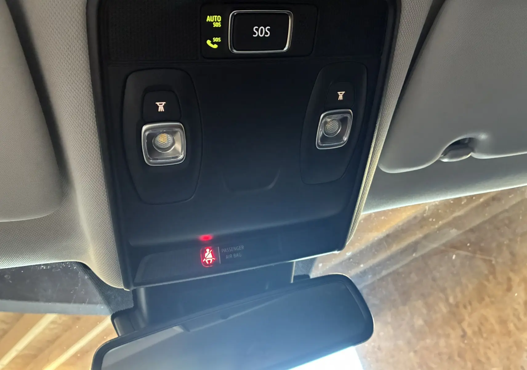 Vue intérieure du plafonnier noir avec boutons d'éclairage et alerte ceinture allumée dans un Renault Captur bleu.