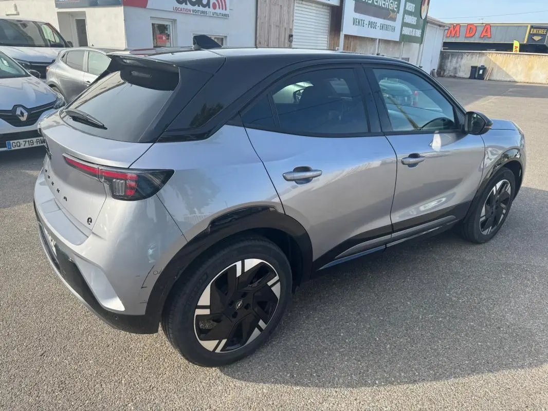 Vue 3/4 arrière droite d’un Opel Mokka électrique gris avec toit noir, jantes alliage 17 pouces et vitres surteintées.