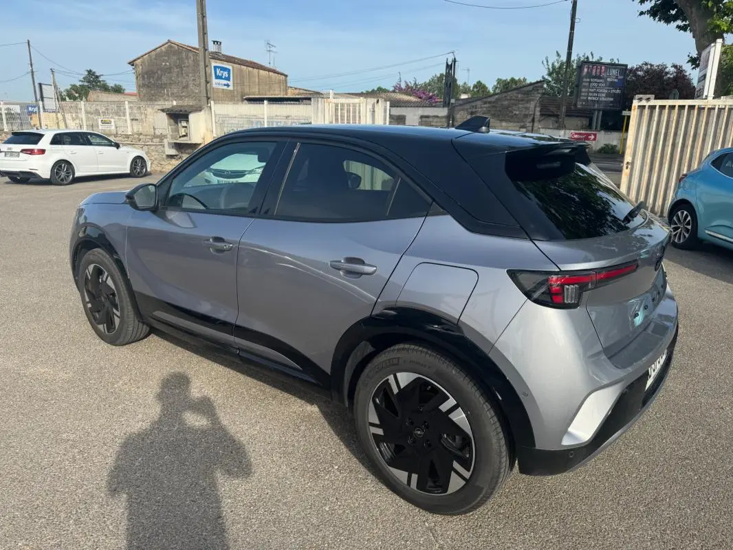 Opel Mokka électrique gris en vue 3/4 arrière droit, avec jantes alliage noires et vitres surteintées.