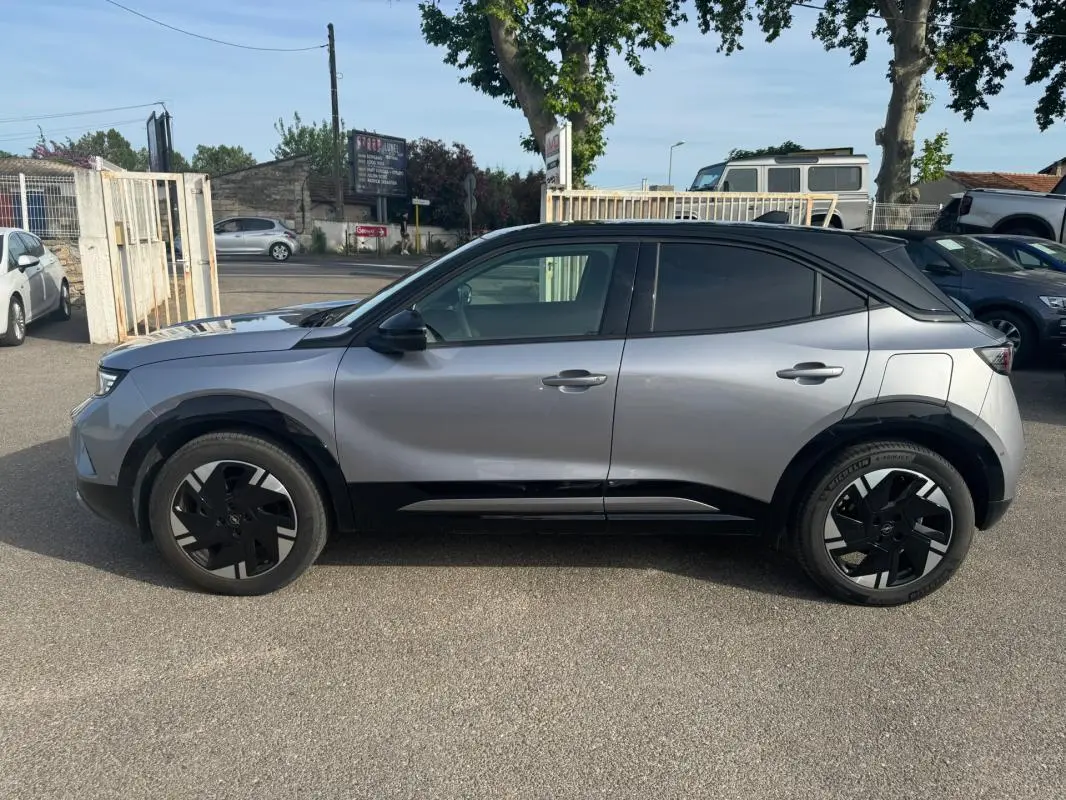 Vue de profil côté gauche d'un Opel Mokka électrique gris avec jantes alliage noires et vitres surteintées.