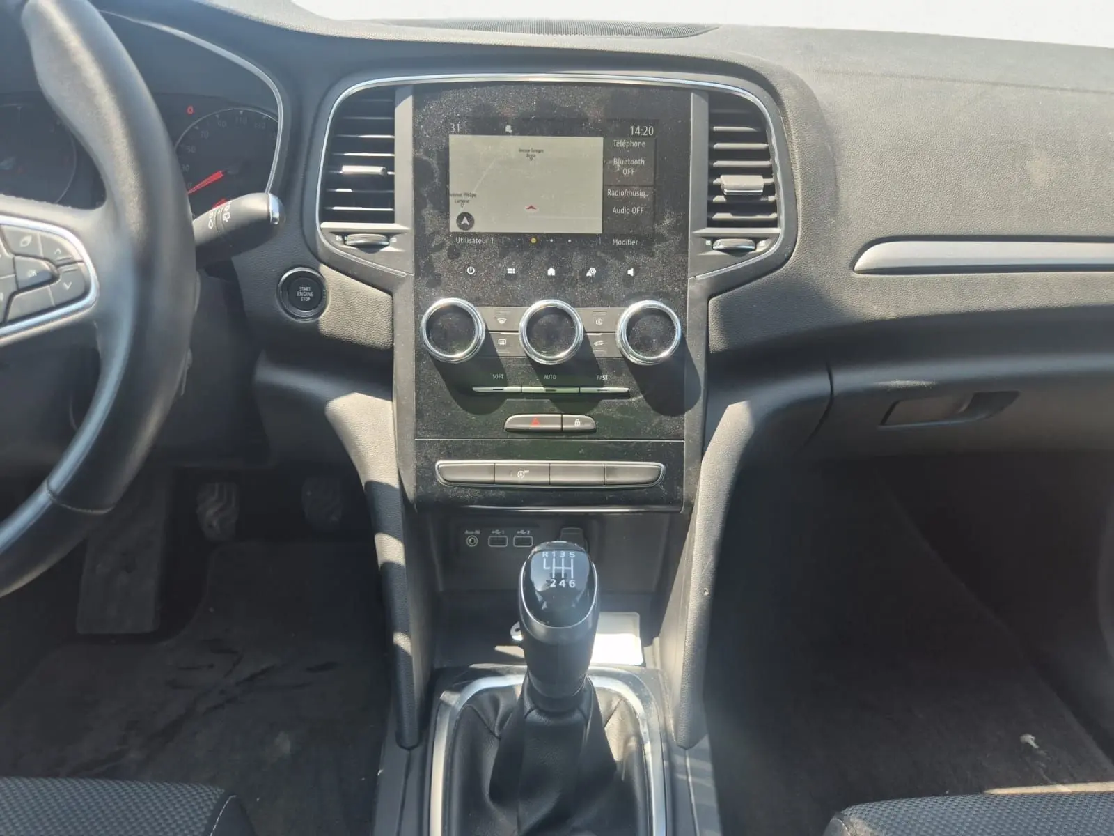 Vue intérieure centrée sur le volant noir de la Renault Mégane blanche 2022 avec tableau de bord et écran tactile visibles.