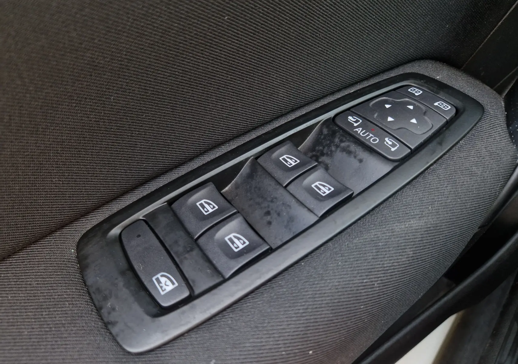 Gros plan sur les commandes électriques des vitres et des rétroviseurs côté conducteur d’une Renault Mégane blanche 2022.