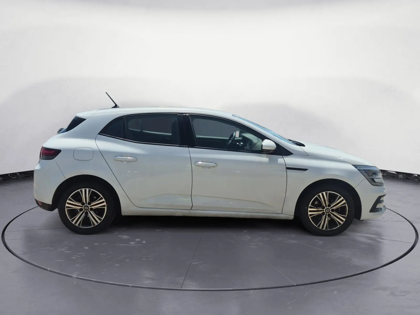 Profil côté gauche d'une Renault Mégane blanche 2022 avec jantes alliage et lignes épurées sur un parking extérieur.