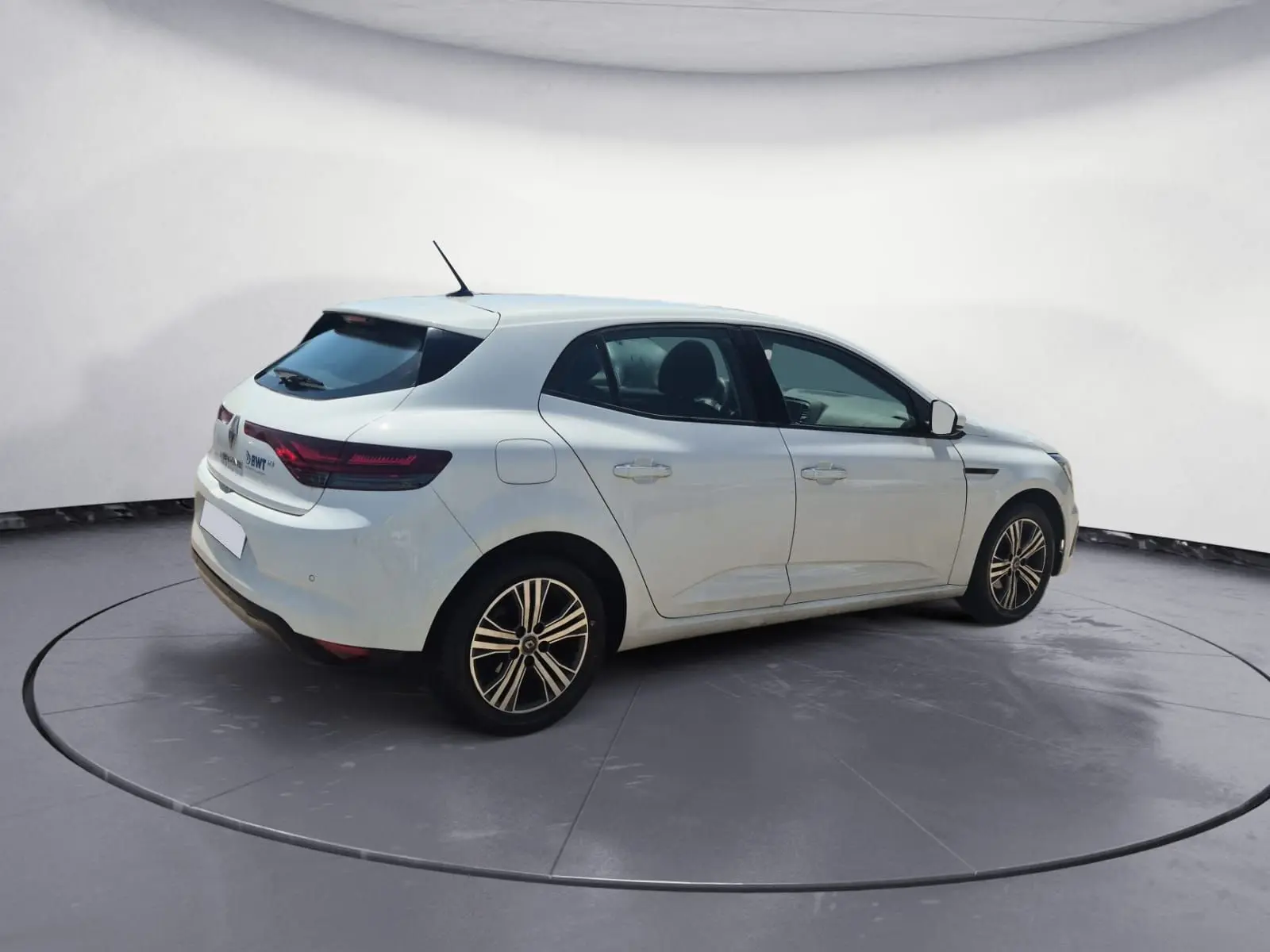 Renault Mégane blanche vue 3/4 arrière droit sur parking, avec feux arrière LED et jantes alliage 16 pouces.