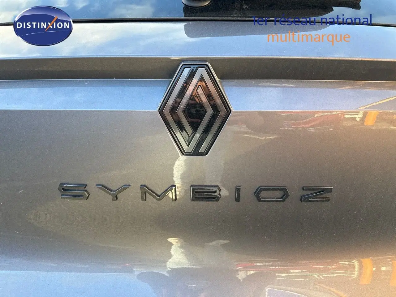 Gros plan sur le logo Renault et le nom Symbioz sur le hayon gris cassiope du SUV hybride 2024.