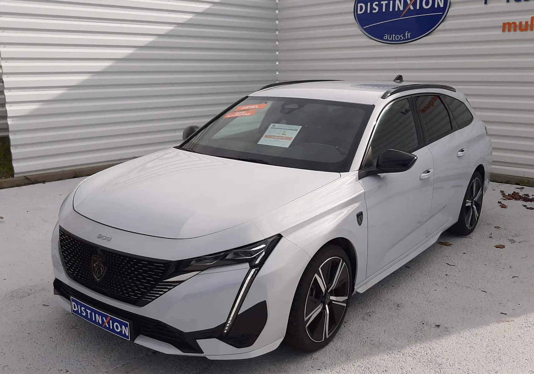 Peugeot 308 SW blanc Okenite vue 3/4 avant droit, avec calandre noire et jantes alliage bicolores.