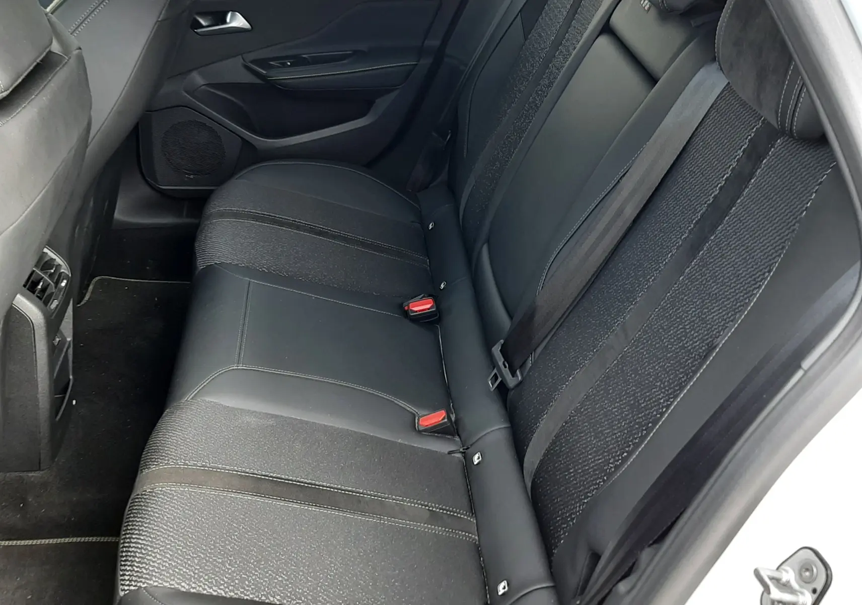Vue intérieure côté droit des sièges arrière noirs en cuir et tissu de la Peugeot 308 SW blanc Okenite 2024.