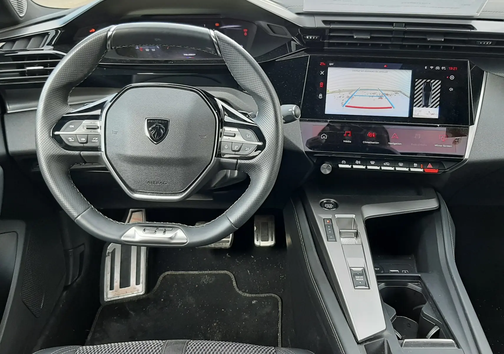 Vue intérieure avant de la Peugeot 308 SW 2024, tableau de bord noir avec volant compact GT et écran tactile central.