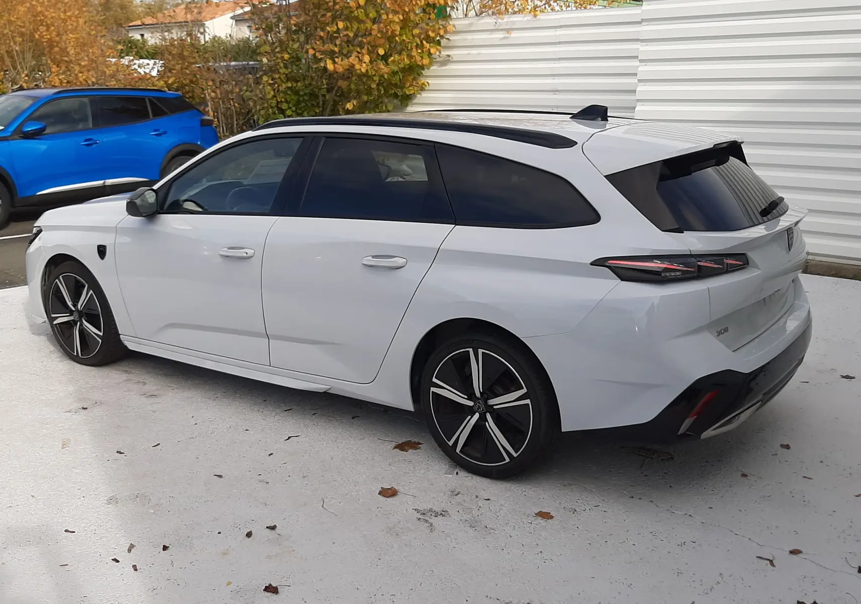 Peugeot 308 SW blanche vue en 3/4 arrière droit, avec toit ouvrant panoramique et jantes alliage noires.