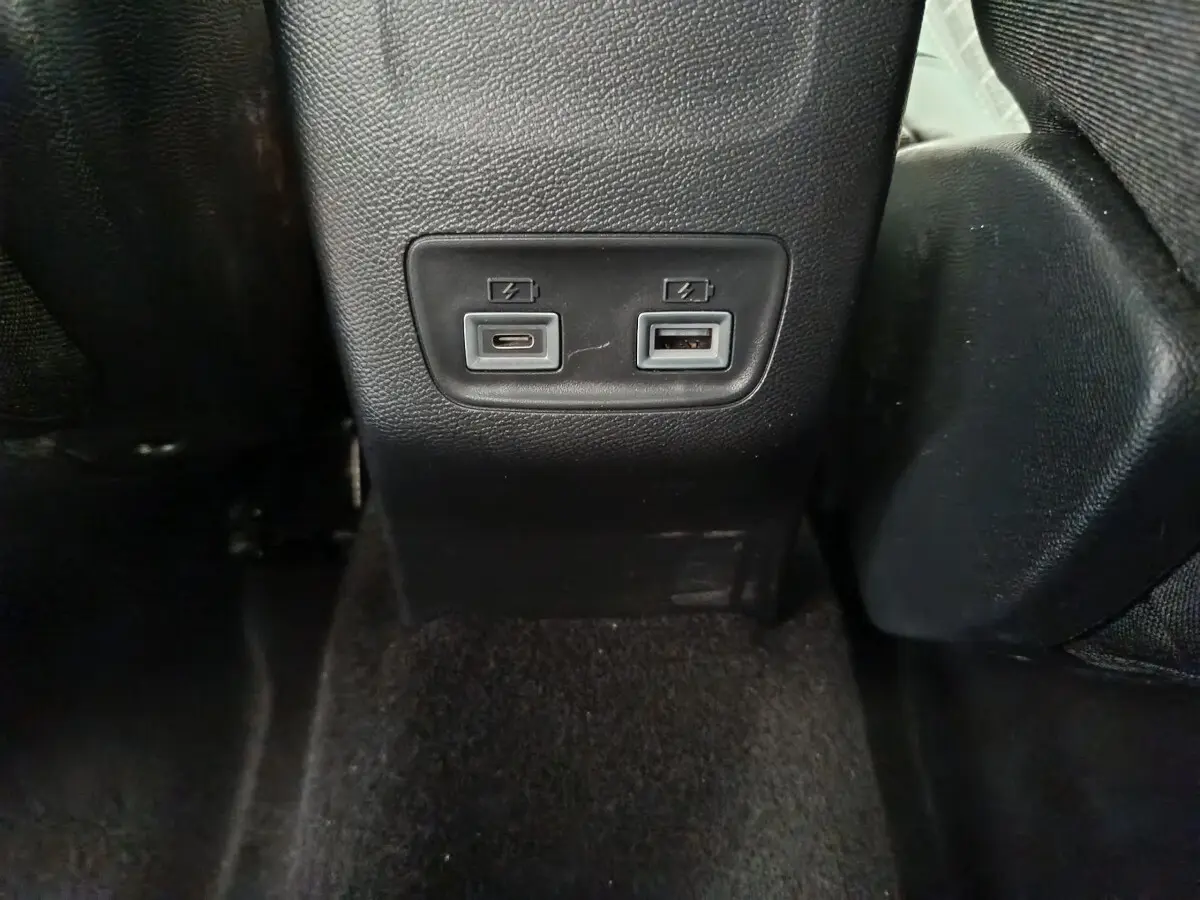 Prise USB type C et USB standard pour recharge, vue rapprochée à l'arrière des sièges noirs d'une Peugeot 208 gris clair.