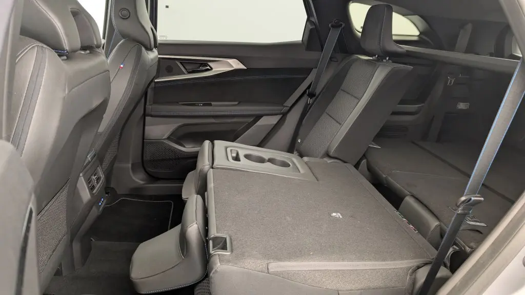 Vue latérale intérieure côté droit du Renault Espace gris Schiste, sièges arrière partiellement rabattus avec accoudoir central visible.