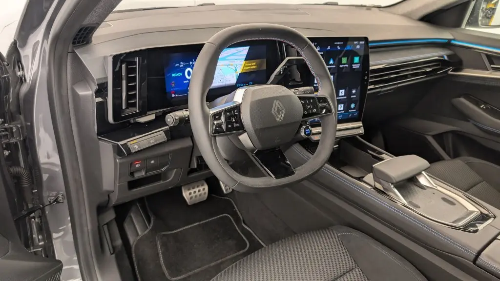 Vue intérieure côté conducteur du Renault Espace E-Tech gris avec tableau de bord numérique et volant multifonction à surpiqûres bleues