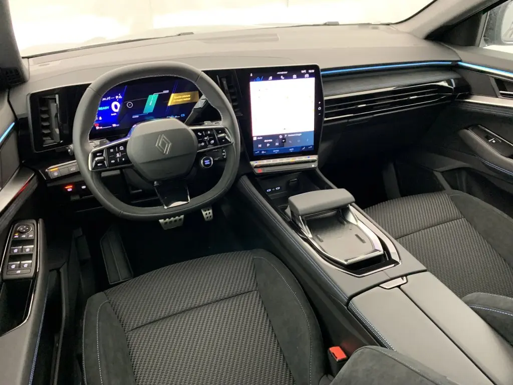 Vue intérieure avant du Renault Espace 2025 E-Tech gris, avec tableau de bord numérique et écran tactile vertical lumineux.