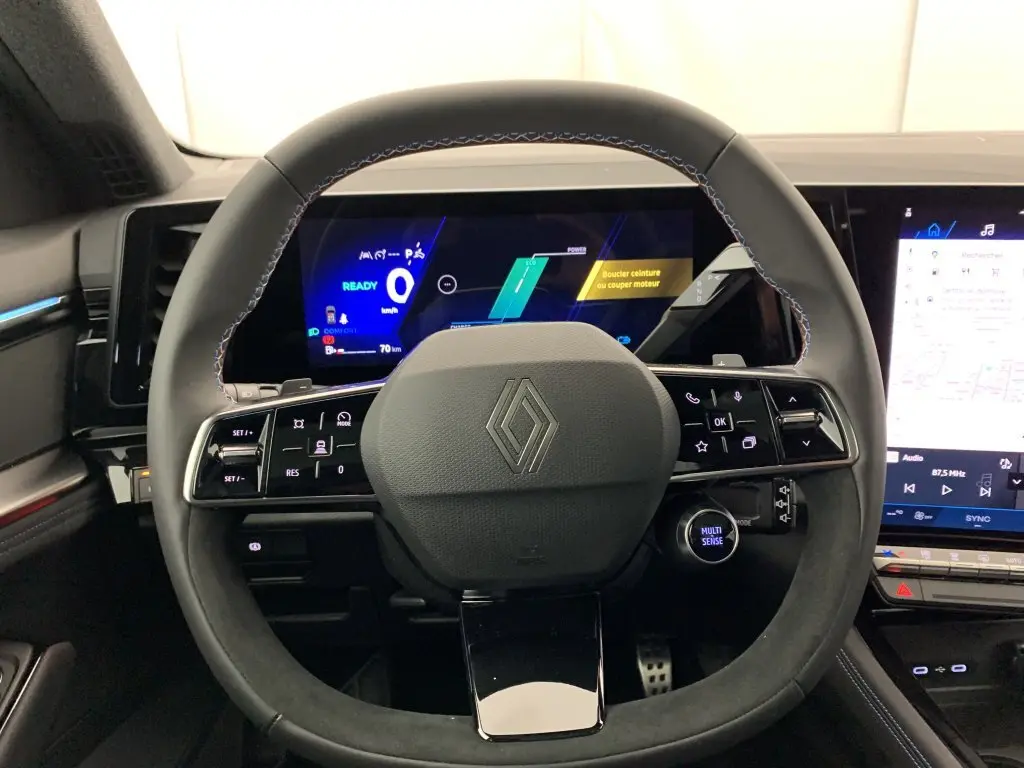 Vue rapprochée du volant noir avec surpiqûres bleues et tableau de bord numérique du Renault Espace E-Tech Gris Schiste.