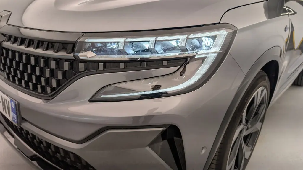 Gros plan sur l'avant droit gris schiste du Renault Espace E-Tech avec calandre à damiers et feux LED distinctifs.