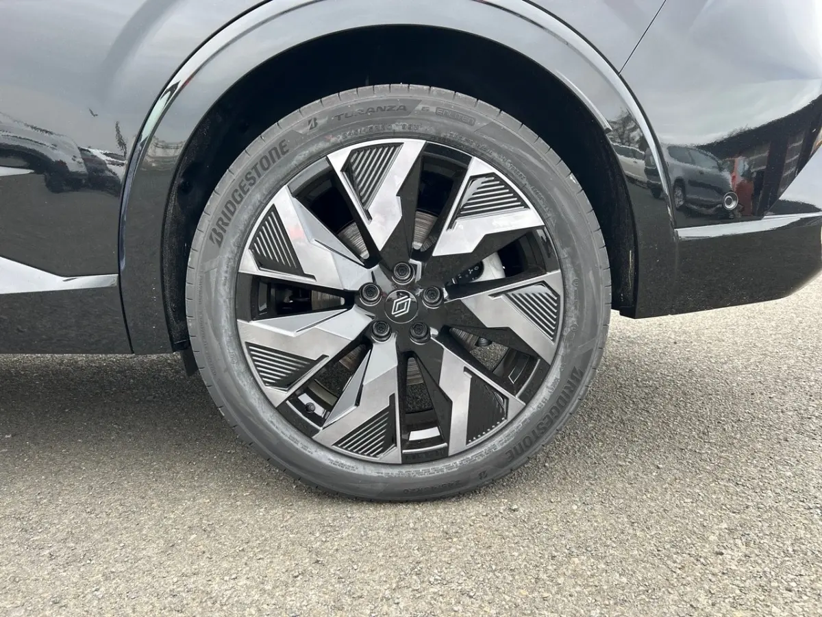 Gros plan sur la roue arrière droite noire d'une Renault Rafale esprit Alpine avec jante au design géométrique bicolore.