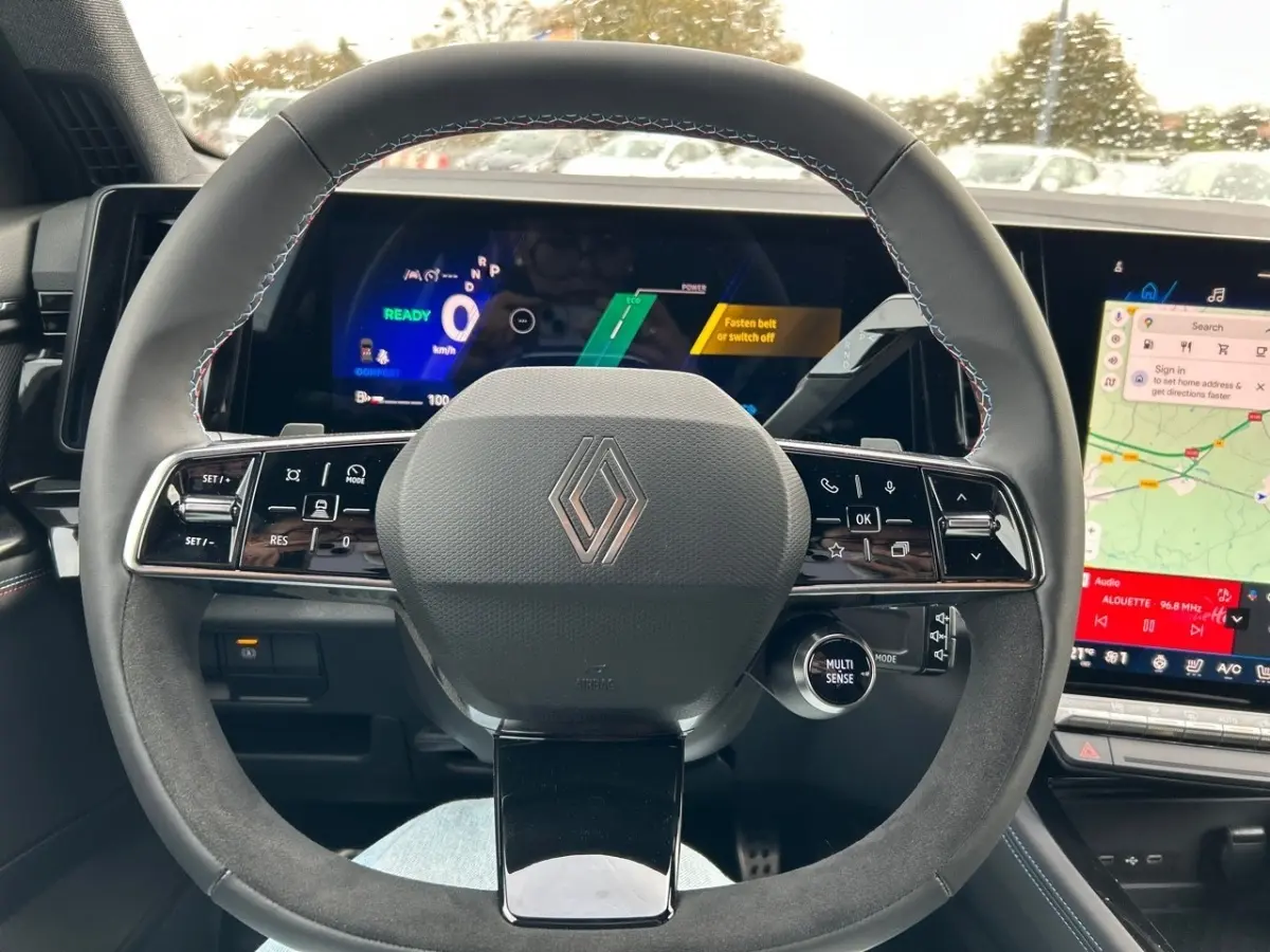 Vue intérieure centrée sur le volant en suède noir du Renault Rafale esprit Alpine avec tableau de bord numérique et écran tactile.