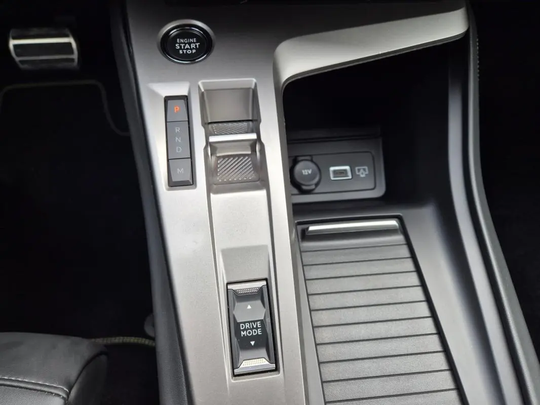 Vue rapprochée de la console centrale argentée du Peugeot 408 Hybrid 136 e-DCS6 GT avec levier de vitesse et bouton Drive Mode.