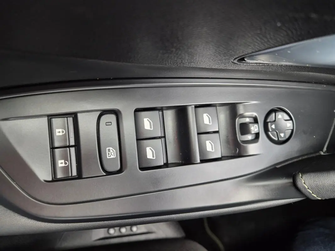 Vue rapprochée des commandes de lève-vitres et rétroviseurs côté conducteur d’une Peugeot 408 Hybrid 136 e-DCS6 GT noire.