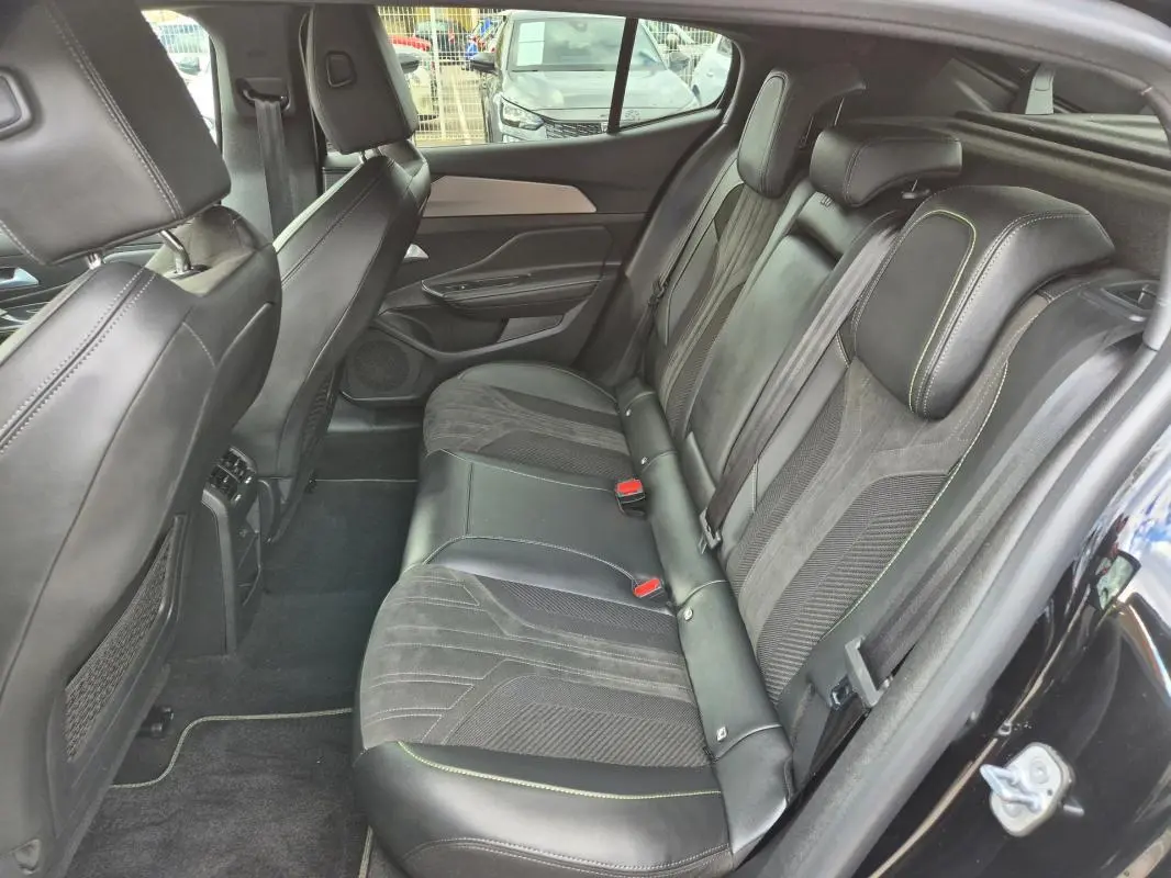 Vue intérieure côté droit des sièges arrière en cuir noir avec surpiqûres vertes du Peugeot 408 Hybrid 2024.